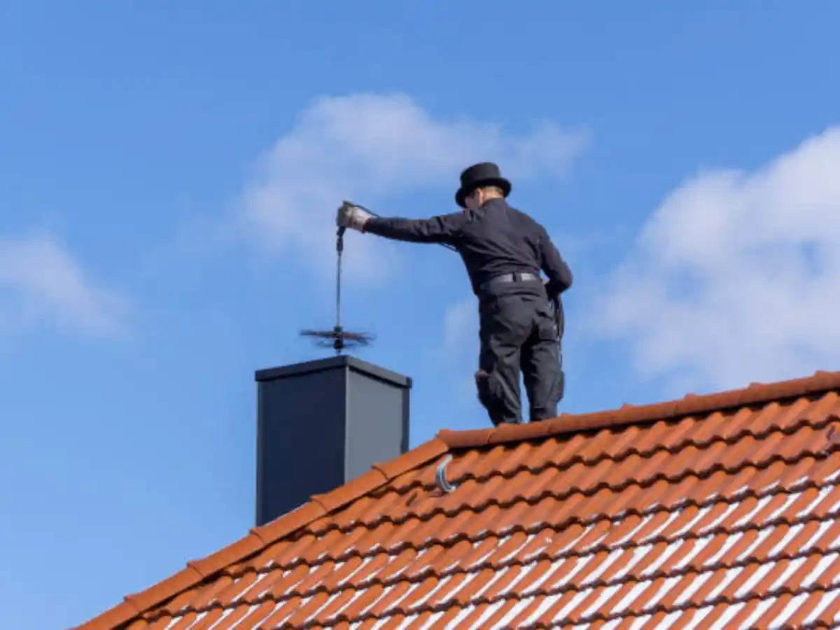 Technician sweeping a rooftop chimney